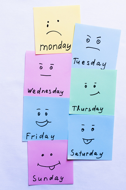 vista superior de notas de papel com nomes de dia e smileys com emoções diferentes no fundo branco - Foto, Imagem
