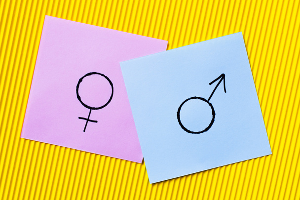 вид фиолетовых карточек с символами гендерной идентичности на желтом текстурированном фоне - Фото, изображение