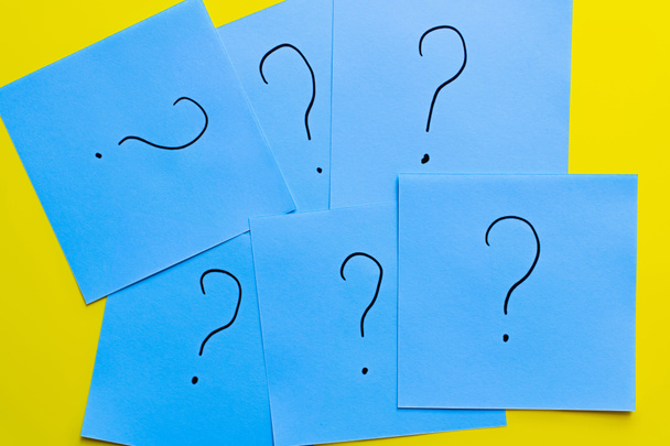 top view of question marks written on blue cards on yellow background - Fotó, kép
