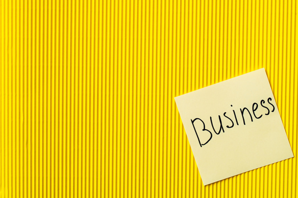 top view of paper with handwritten word business on yellow textured background - Photo, Image