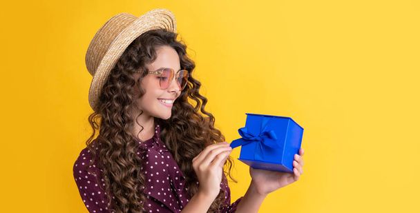 glad kid with curly hair hold present box on yellow background. - Fotó, kép