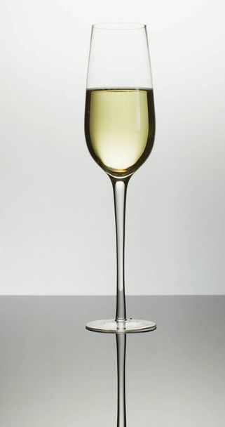 Vertical image of single tulip glass of white wine or champagne on white background. luxury, leisure and celebration. - Foto, Imagem