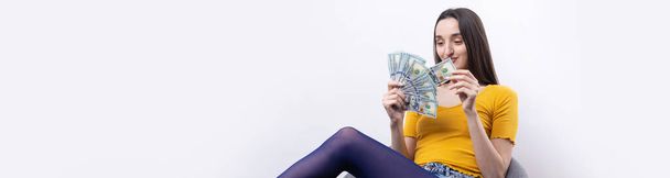Foto de mulher rica em roupas simples segurando fã de dinheiro dólar isolado no fundo branco - Foto, Imagem