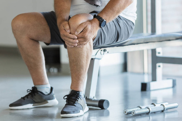 Active senior man in gym with knee injury - 写真・画像