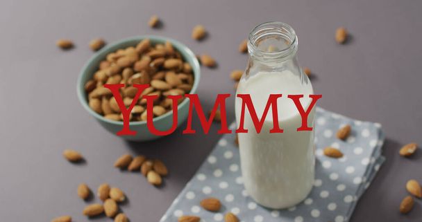 Image of yummy text over milk and nuts. world milk day and celebration concept digitally generated image. - Foto, Imagem