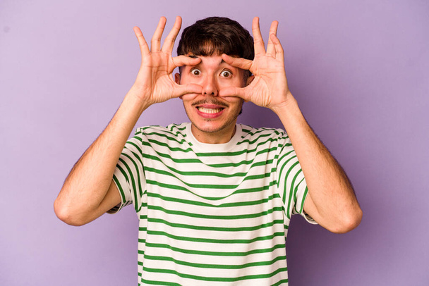 Young caucasian man isolated on purple background keeping eyes opened to find a success opportunity. - Fotografie, Obrázek