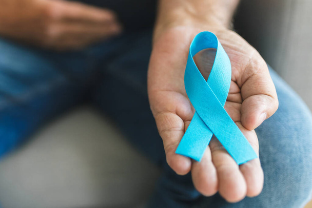 Senior man holding a blue cancer awareness ribbon in hand - Valokuva, kuva