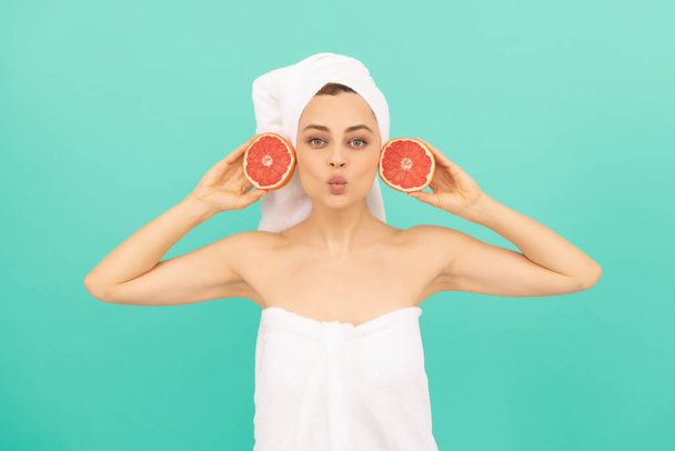 funny young woman in towel after shower with grapefruit on blue background. - Photo, Image