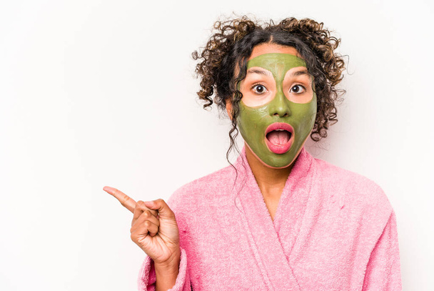Young hispanic woman wearing a facial mask isolated on white background pointing to the side - Photo, Image