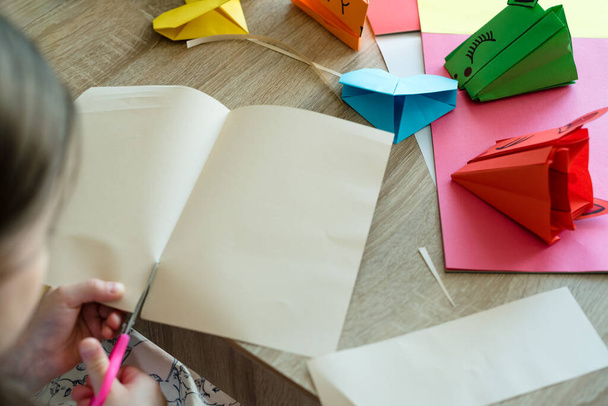 Las manos de los niños hacen origami de papel de colores. Origami corazones y dragones. Lección de origami. - Foto, imagen