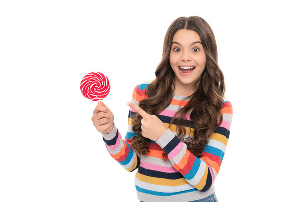 look there. yummy. amazed girl pointing finger on lollipop. lollipop child. kid in colorful sweater hold lollypop. sugar candy on stick. caramel candy shop. childhood. teen dental care. sweet tooth. - 写真・画像