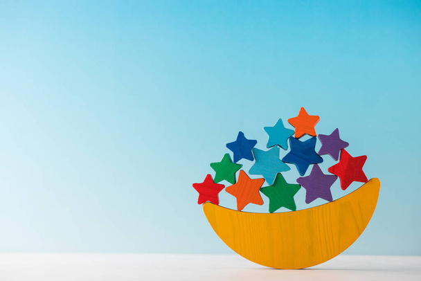 Childrens wooden educational toy balancer in the form of a month and stars on a blue background. Montessori toys. Copy space. - Фото, зображення