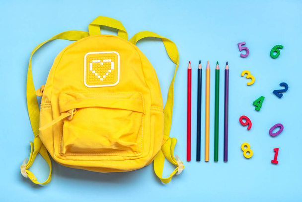 Back to school, education concept. Yellow backpack, pencils, numbers isolated on blue background. Top view. Copy space Flat lay composition. - Photo, Image
