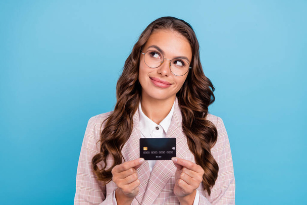 Portrait of attractive curious cheerful woman economist holding bank card contemplate isolated over bright blue color background. - Foto, Bild