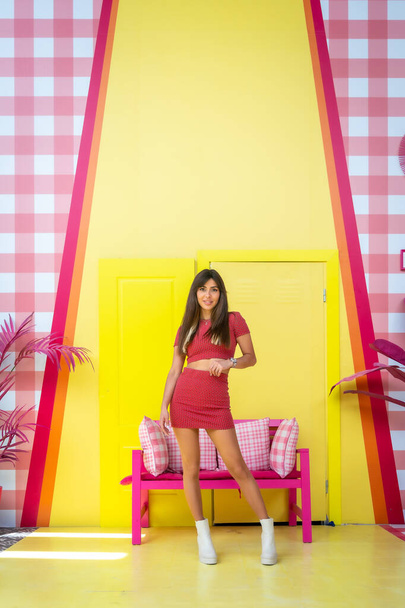 Portrait of a brunette caucasian girl by the bench in a pink and yellow decor, posed in a vintage fashion - Fotoğraf, Görsel