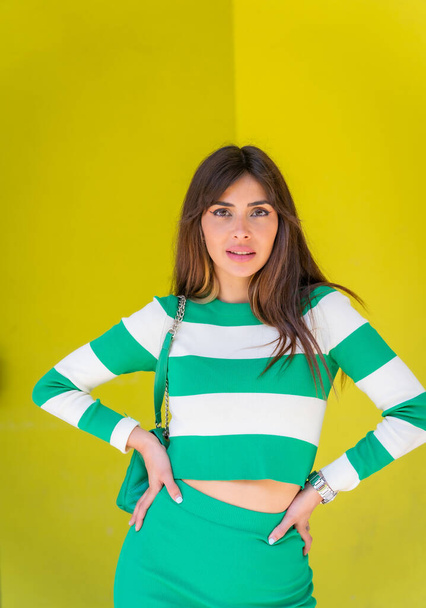Portrait of a caucasian girl with a white striped sweater on a green background, posed looking at the camera - Фото, изображение