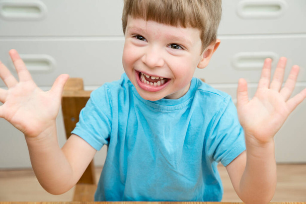 Back to school. Kid sits by the table in nursery or kindergarten. Emotions. Happy face expression. Boy smiling with open palms. - Foto, afbeelding