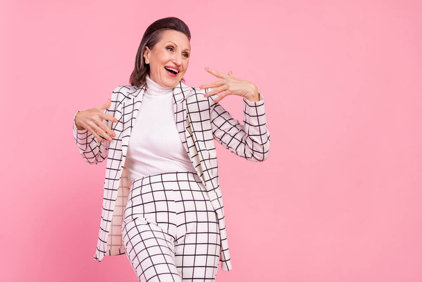 Photo of funky smiling artistic dancing mature lady wear checkered formalwear isolated on pink color background. - Foto, Imagen