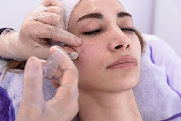 Kosmetolog provádí omlazující anti-vráskové výplňové injekce s plnivem kyseliny hyaluronové do ženské tváře Dámská estetická kosmetika v salonu krásy. - Fotografie, Obrázek