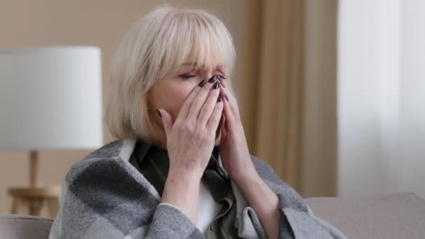 Choroba dojrzała 60s kobieta cierpi na biegnący nos dostał grypy przeziębienie kichanie chore objawy problemy zdrowotne sezonowa alergia kaszel. Stara starsza pani rasy kaukaskiej sama w domu kicha z powodu choroby wirusowej19 - Materiał filmowy, wideo