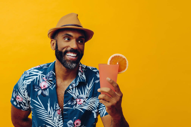 красивий афроамериканський чоловік у гаїтянській сорочці та капелюсі з апельсиновим соком, що позує на жовтому фоні
 - Фото, зображення