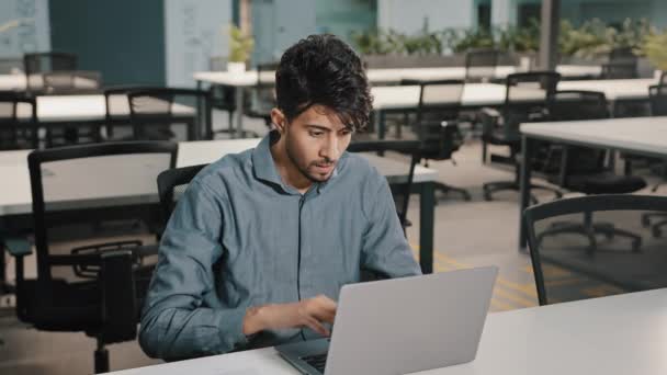 Nuori mies arabialainen työntekijä liikemies intialainen mies yrittäjä kirjoittamalla kannettavan tietokoneen näppäimistön kopio tekstiä verkossa taloudellinen sovellus ikionnellinen kaveri saada voittoa saada kaupallista voittoa tyytyväinen valmis työ - Materiaali, video