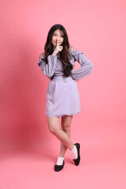 The cute young Asian woman with preppy dressed standing on the pink background. - Photo, Image
