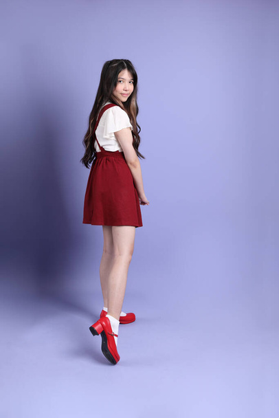 The cute young Asian woman with preppy dressed standing on the purple background. - Photo, Image