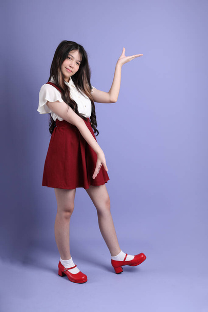 The cute young Asian woman with preppy dressed standing on the purple background. - Foto, Imagem