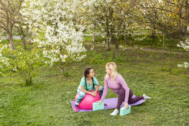 Mutter und Tochter im Freien beim Yoga, gesunder Lebensstil - Foto, Bild
