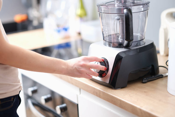 Frau schaltet Mixer ein, um Produkte zu mischen. Küchenmixer-Konzept - Foto, Bild