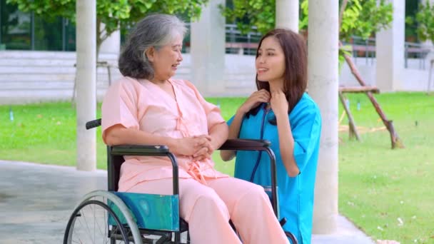 Азиатский заботливый ухаживающий или медсестра заботится о пожилом азиатском пациенте в инвалидном кресле. Концепция счастливого выхода на пенсию с заботой от сиделки и сбережений и старшего медицинского страхования. уход за пожилыми - Кадры, видео