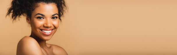 retrato de mujer americana africana alegre con hombros desnudos y piel perfecta aislada en beige, bandera - Foto, Imagen