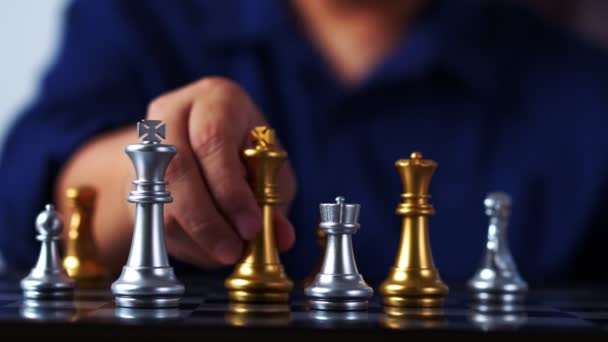 Gros plan des mains d'un homme d'affaires se déplaçant roi échecs dorés pour vaincre l'adversaire le jeu d'échecs est l'analyse de développement, la stratégie et le plan, le concept de gestion ou de leadership. - Séquence, vidéo