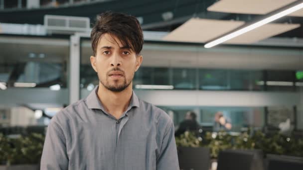 Portrait of young arab serious indian man businessman in formal shirt stand indoors posing profile look away turn head at camera sad pensive thoughtful brunet guy feel desperate nervous has depression - Footage, Video