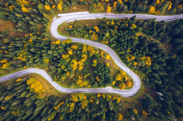 Curved bending road in the forest. Aerial image of a road. Forrest pattern. Scenic curvy road seen from a drone in autumn. Aerial top down view of zig zag winding mountain road, drone shot. - Photo, Image