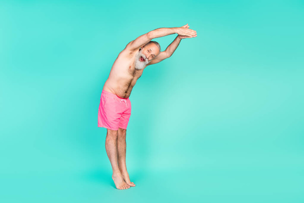 Profile photo of excited funky old man jump pool open mouth wear pink shorts isolated teal color background. - Photo, Image