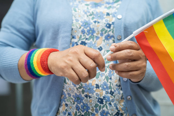 ゲイ、レズビアン、バイセクシャル、トランスジェンダー、人権の6月の社会でLGBTプライド月間のシンボルである虹の旗の心を持つアジアの女性. - 写真・画像