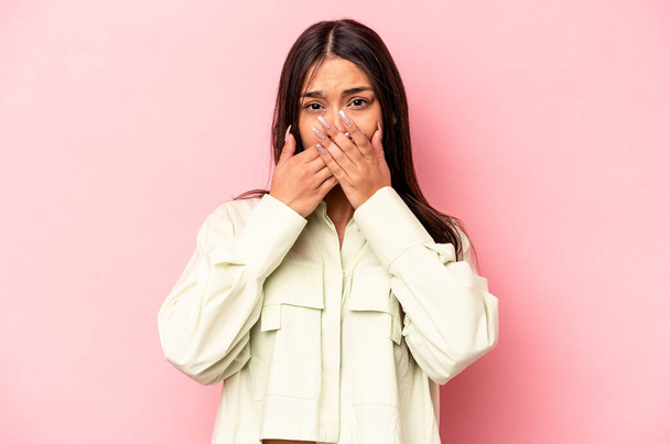 Mujer hispana joven aislada sobre fondo rosa impactada cubriendo la boca con las manos. - Foto, Imagen