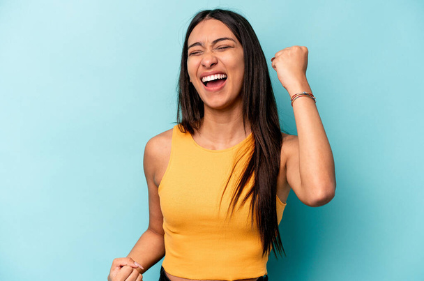 Young hispanic woman isolated on blue background cheering carefree and excited. Victory concept. - Photo, Image