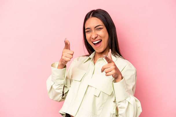 Young hispanic woman isolated on pink background cheerful smiles pointing to front. - Foto, Imagen