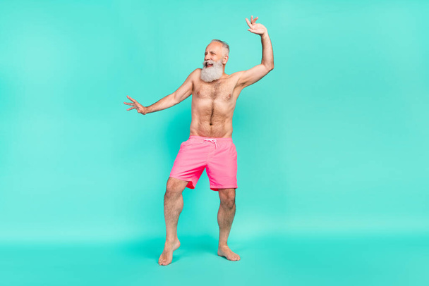 Foto von lustigen positiven Rentner Retro-Mann tanzen Strandparty heben die Hände isoliert türkisfarbenen Hintergrund. - Foto, Bild