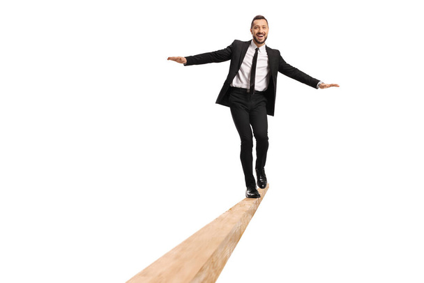 Full length portrait of a businessman walking on a wooden beam isolated on white background - Foto, immagini
