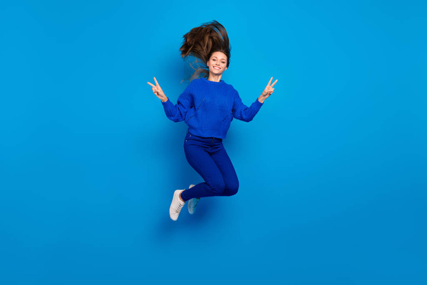 Full length body size view of attractive cheery girl jumping showing v-sign having fun isolated on bright blue color background. - Foto, Imagem