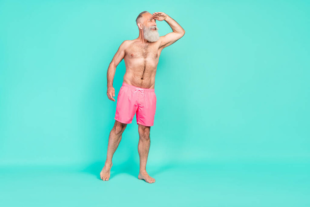 Photo of interested funny dreamy man palm forehead look empty space wear pink shorts isolated turquoise color background. - Zdjęcie, obraz