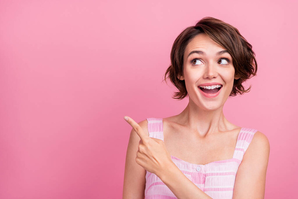 Photo of young cheerful lady wondered look indicate finger empty space promotion advert advise isolated over pink color background. - Zdjęcie, obraz