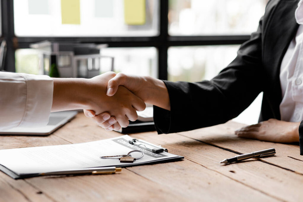 The salesperson of the housing estate in the project and the customer shake hands after successfully signing the contract. Concept of selling housing estates and real estate. - Foto, Imagem