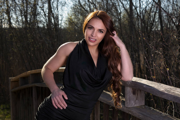 young woman standing outside posing in nature spring park wearing black dress - Photo, Image