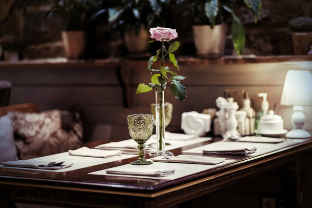 Ein gemusterter grüner Glaskelch steht auf einem Serviertisch in einem Café mit Vintage-Luxusinterieur. Selektiver Fokus. Glaskelch im Fokus - Foto, Bild
