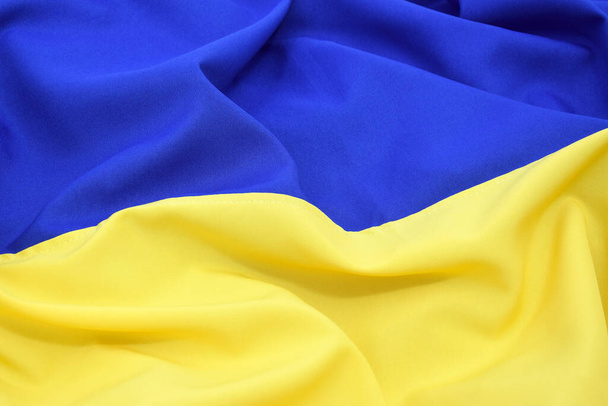 Fabric bent national flag of Ukraine, UA. Blue and yellow colors. Close-up, background. - Fotó, kép